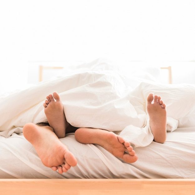 Couple lying barefoot on bed Free Photo