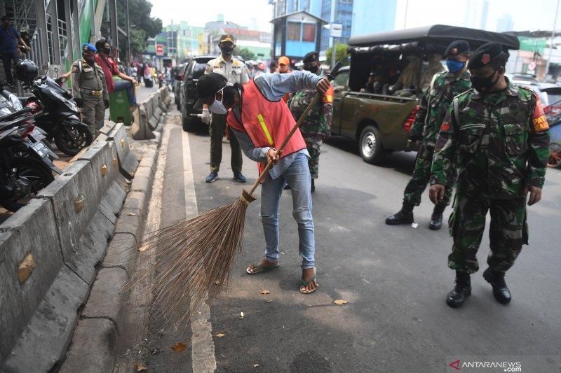 Pelanggar aturan Pembatasan Sosial Berskala Nesar (PSBB) melaksanakan sanksi kerja sosial dengan menyapu sampah di kawasan Sabang, Jakarta, Senin (10/8/2020).